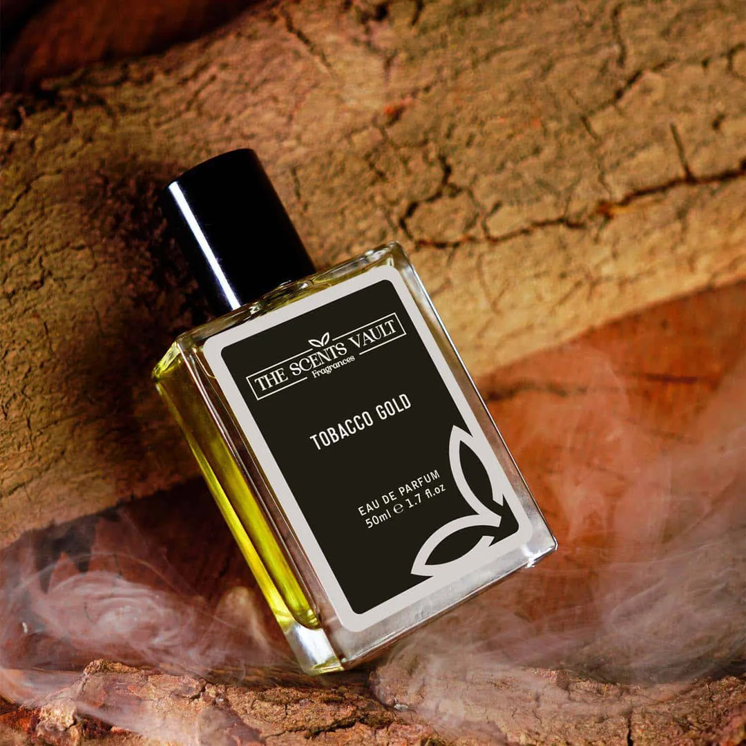 Tobacco Gold eau de parfum by The Scents Vault on wooden surface with a smoky haze, 50ml bottle.